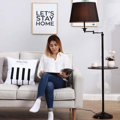 A woman sits on a sofa and reads a book in a cozy living room under a Rotating Floor Lamp with Mini Shelf.