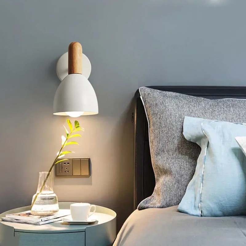 Modern bedroom with a wall lamp, side table, and bed with pillows.