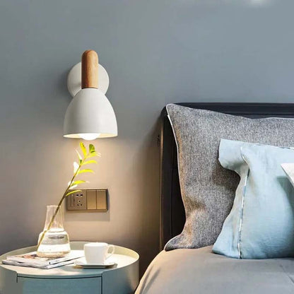 Modern bedroom with a wall lamp, side table, and bed with pillows.