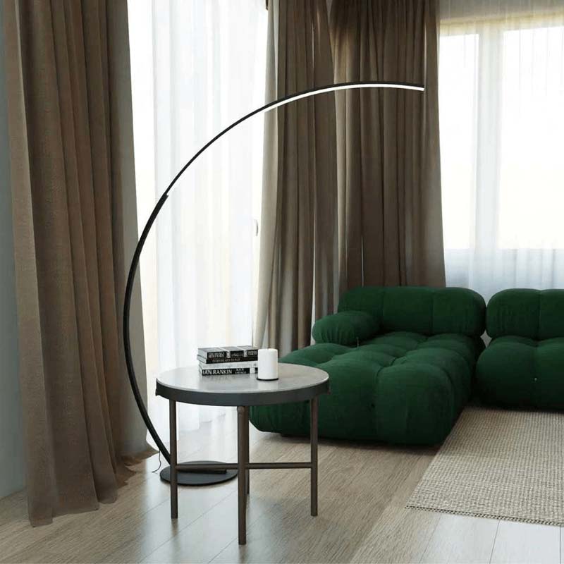 Arc floor lamp in a living room with a green sofa and a small round table
