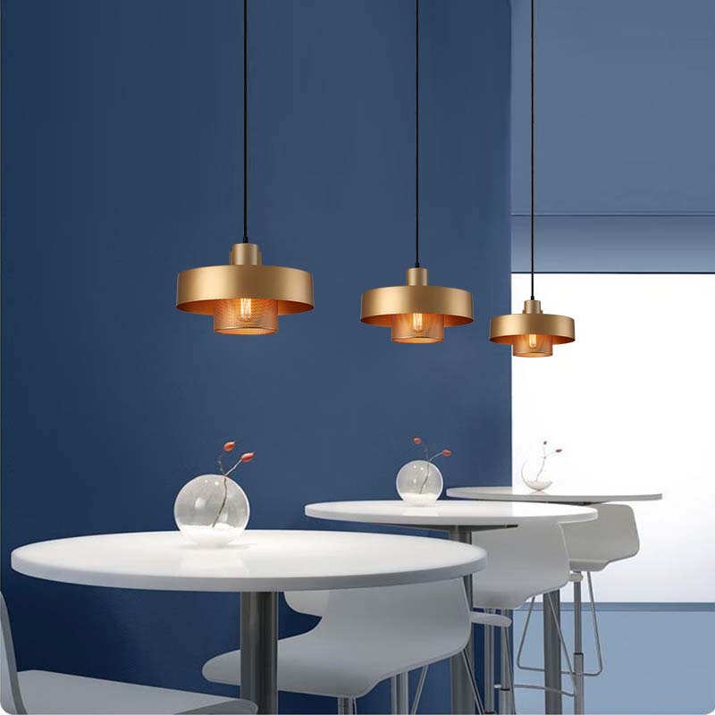 Black & Gold Pendant Light with a gold finish hanging above round tables in a modern café interior with blue walls.