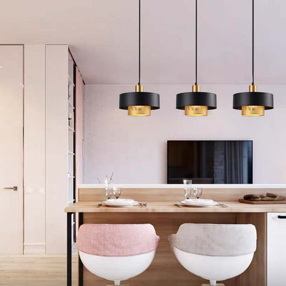 Black & Gold Pendant Light with a black outer shade and gold inner diffuser hanging above a kitchen bar counter in a bright modern interior.