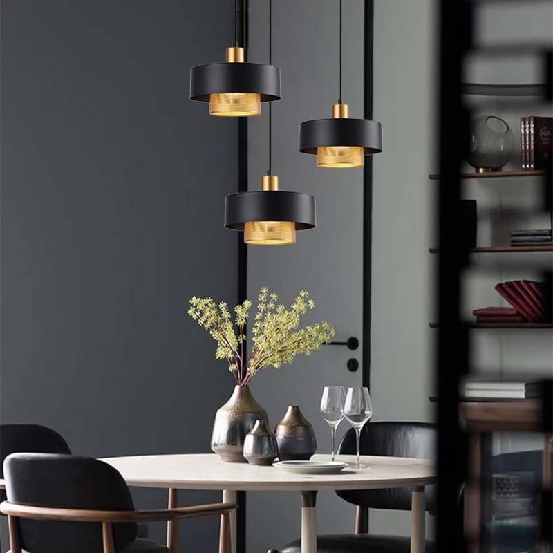 Contemporary dining area with a Black & Gold Pendant Light, a round table, and decorative accents.
