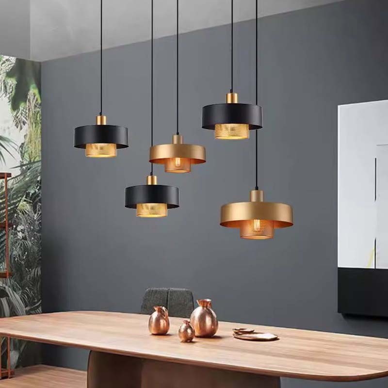 Black & Gold Pendant Lights hang above a dining table with decorative vases against a gray wall.