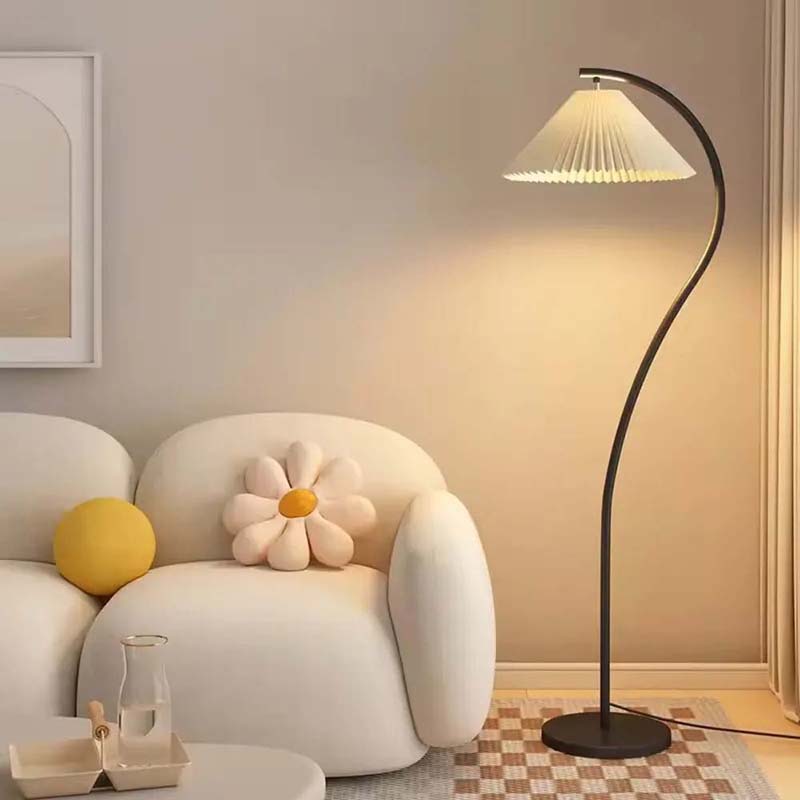 Black floor lamp with soft diffused light next to a sofa.