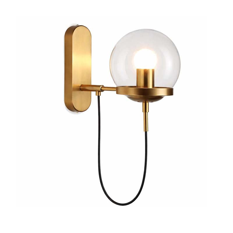 Gold wall-mounted lamp with a clear glass shade on a white background