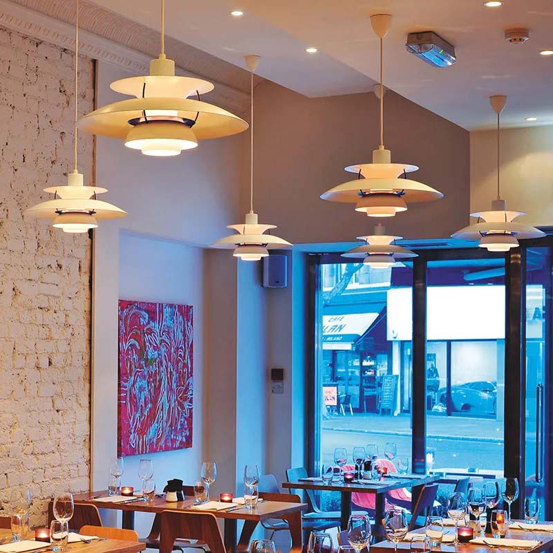 Modern restaurant interior with pendant lights, tables, and a large window.