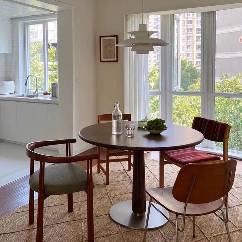 Cascade Pendant Light in a dining area with a round table and chairs in a well-lit room with large windows.