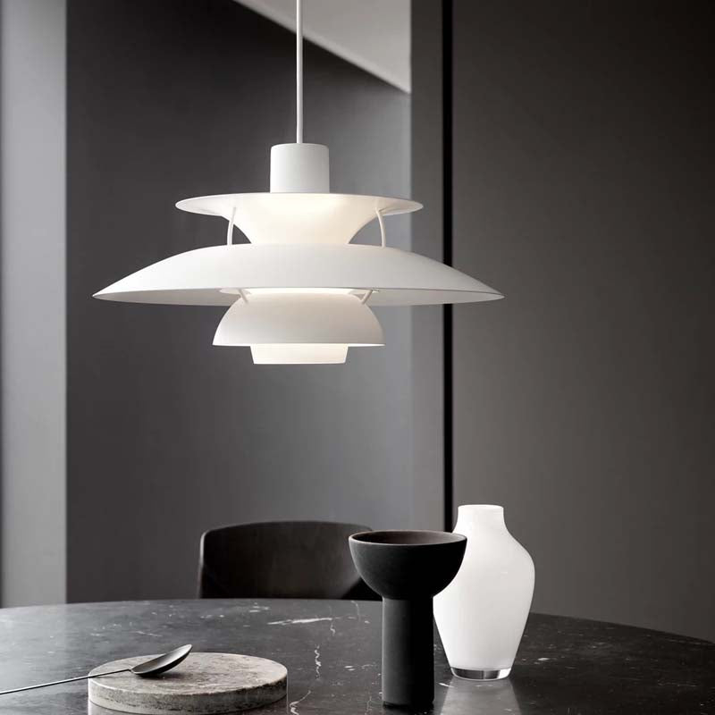 Modern pendant light hanging above a table with decorative items.