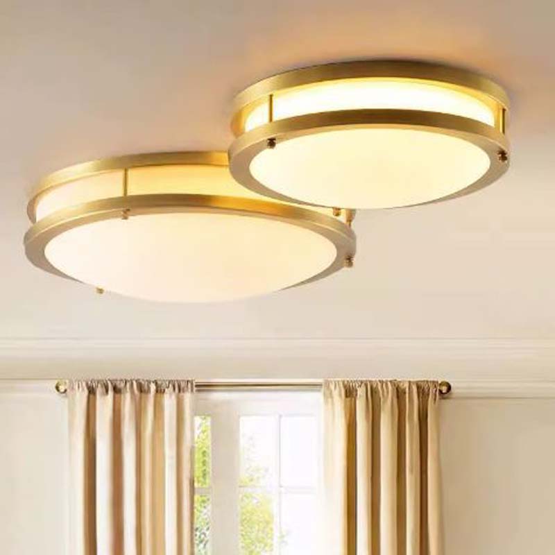 Two gold ceiling lights on a white ceiling with curtains in the background