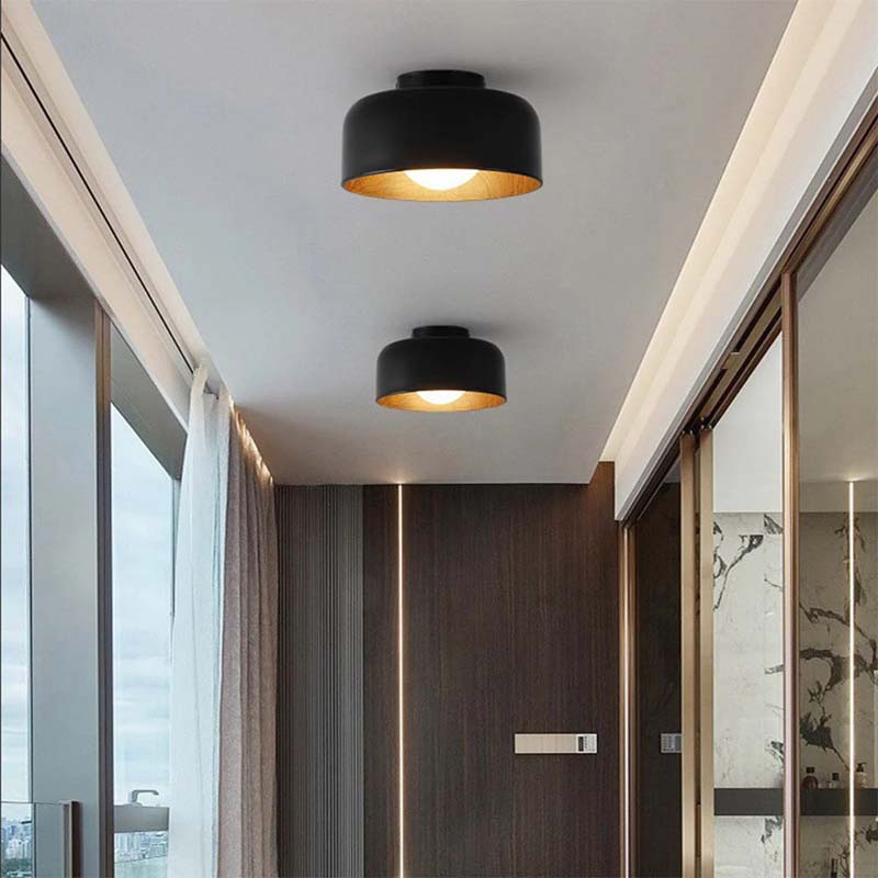 Modern ceiling lights in a room with large windows and wooden paneling.