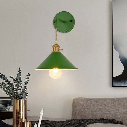 Green wall lamp with gold fixture on a neutral wall in a living room setting.
