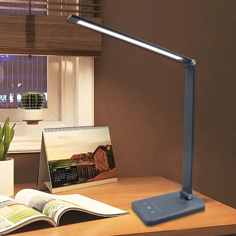 Blue LED desk lamp on a wooden surface with a calendar and magazine in the background.