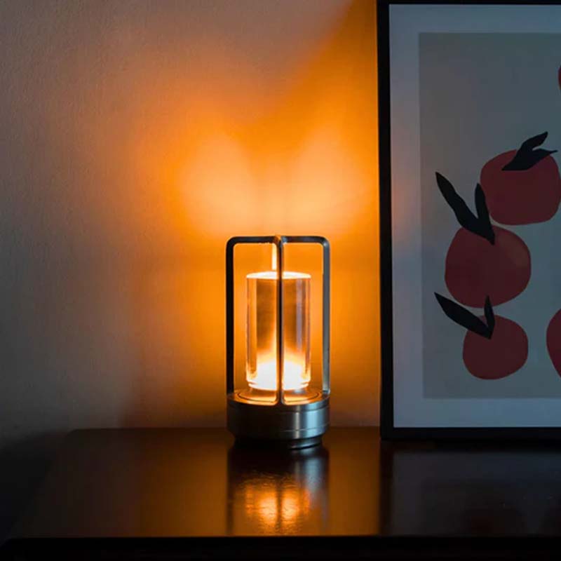 Lantern-shaped lamp casting a warm glow on a wall with a framed picture of apples.