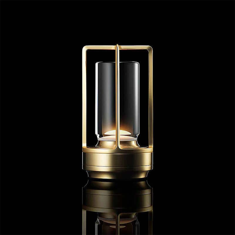 Modern table lamp with gold base and clear glass shade on a black background