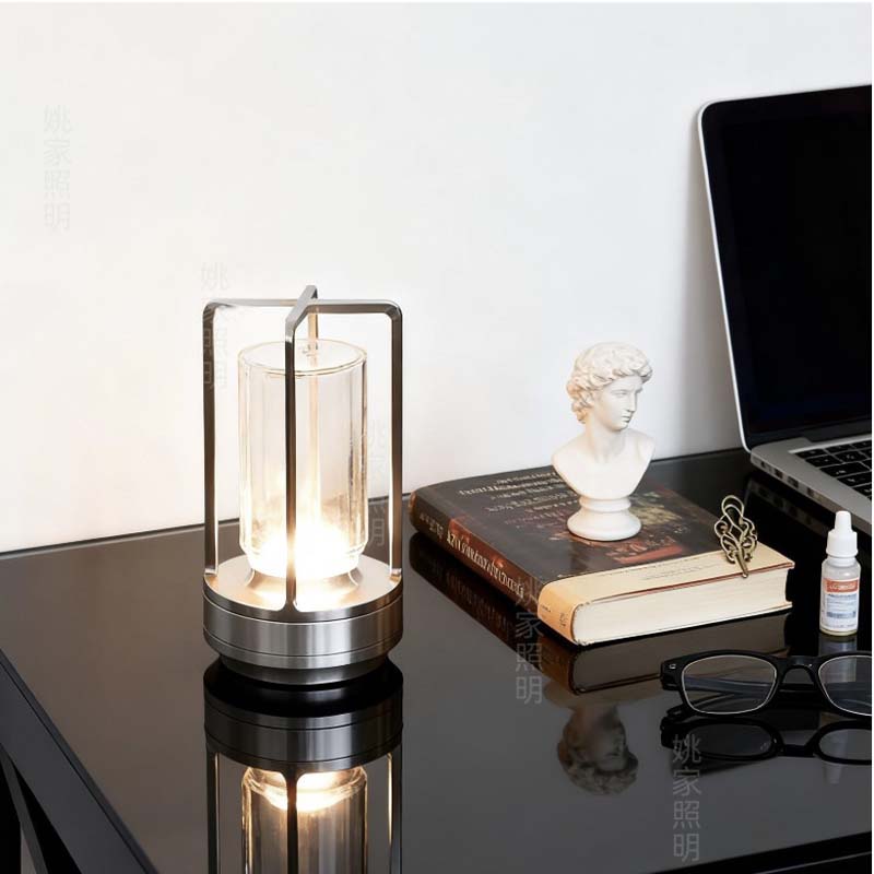 Modern desk lamp on a reflective surface with books and a laptop in the background