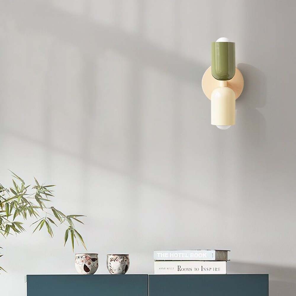 Wall-mounted light fixture with green and beige design on a neutral wall.