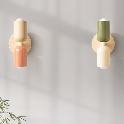 Two wall sconces with colorful cylindrical designs on a plain wall.
