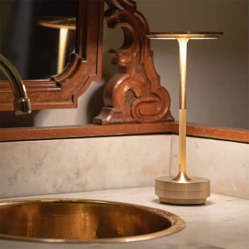 A table lamp on a marble countertop in a bathroom with a mirror in the background.