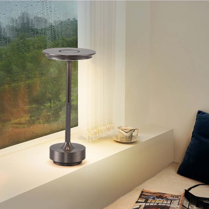 Modern table lamp in a room with a window and a sofa.