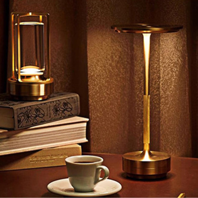 Brass table lamp on a wooden surface with a cup of coffee and books in the background.