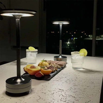 Two table lamps on a table with fruits and drinks at night.