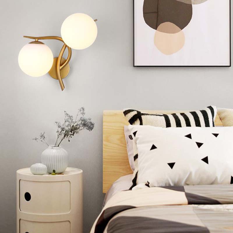Modern bedroom with wall lamp, nightstand, and bed with decorative pillows.