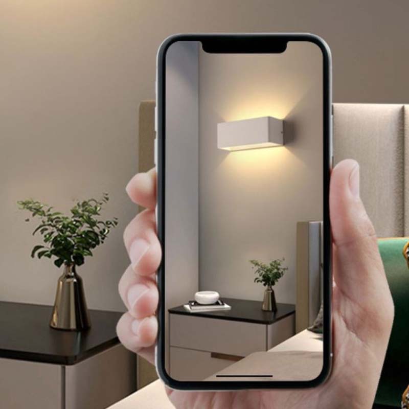 Hand holding a smartphone showing a room with a wall-mounted light fixture.