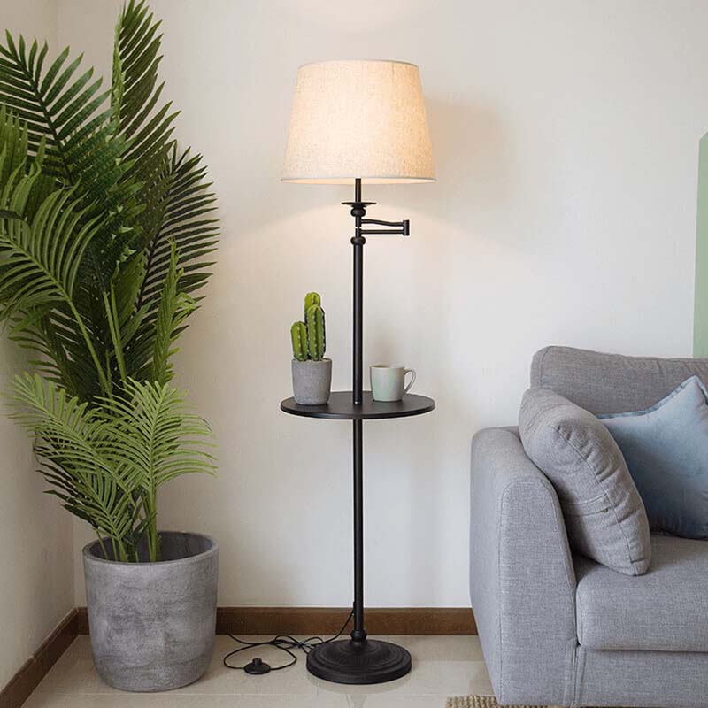 Floor lamp with a small round table next to a potted plant and a gray sofa.