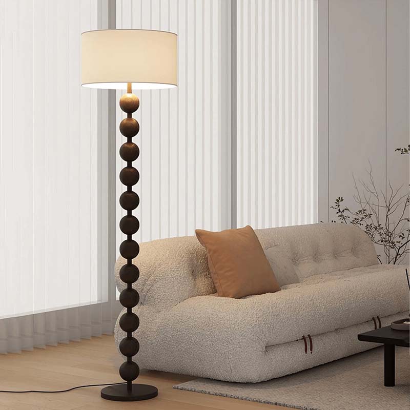 Floor lamp with decorative base next to a beige sofa in a living room setting.