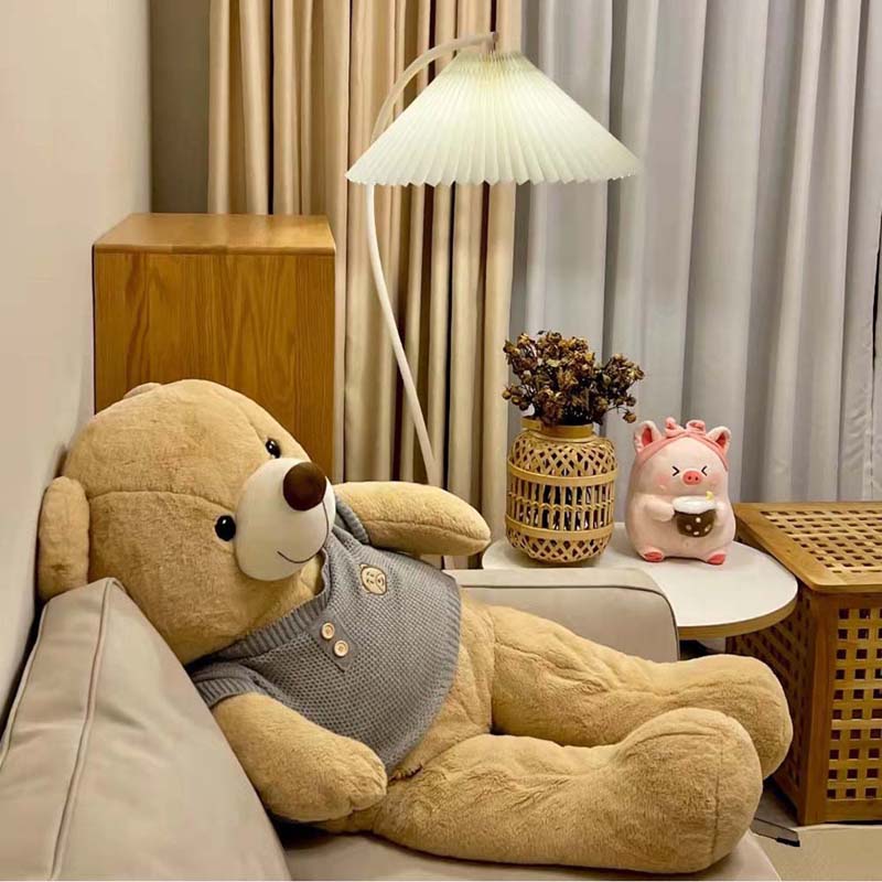 Floor lamp with soft diffused light next to a sofa and decorative elements, creating a cozy atmosphere.