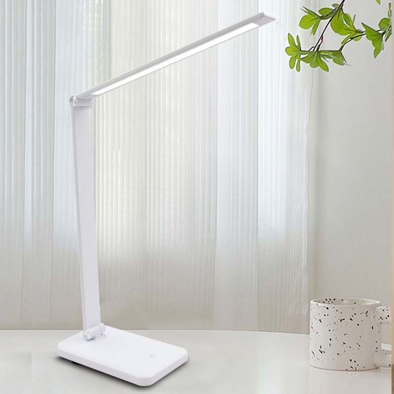 White LED desk lamp on a light surface with a blurred background
