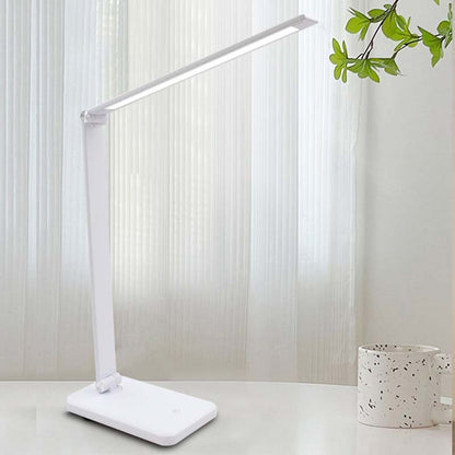 White LED desk lamp on a light surface with a blurred background