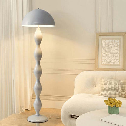 Gray floor lamp in a living room setting with a white sofa and decorative elements.