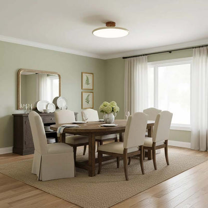 A ceiling lamp in a dining room interior with a wooden table and beige chairs, a large mirror and framed paintings.