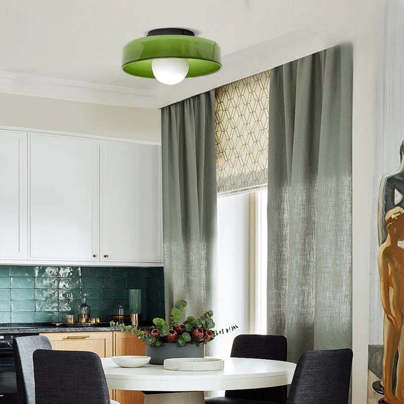 Modern kitchen with white cabinets, green ceiling light, and a dining table with chairs.