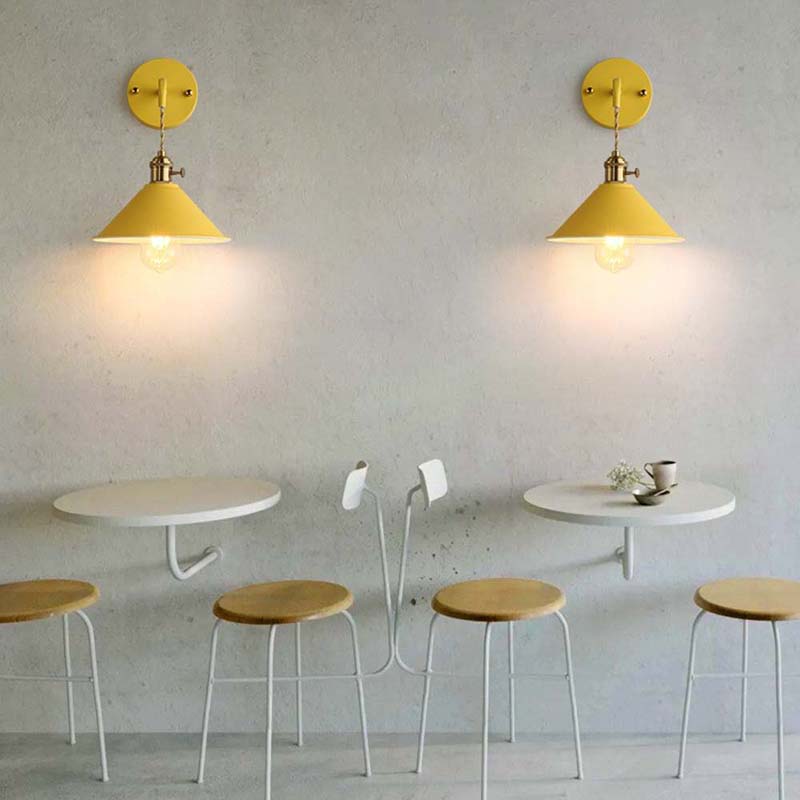 Small cafe setup with round tables, stools, and yellow wall lights.