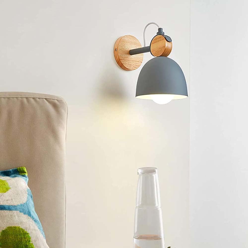 Wall-mounted lamp with wooden base and gray shade on a white wall.