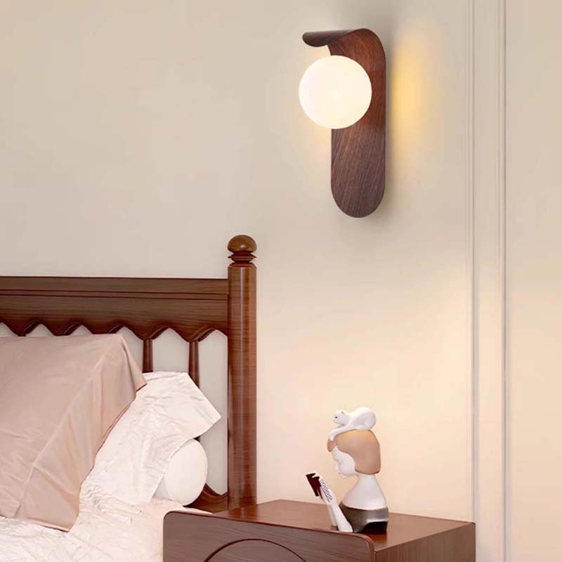 Wall-mounted lamp above a wooden nightstand with a decorative figure in a bedroom setting.