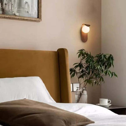 Bedroom with brown headboard, white bedding, and wall-mounted light fixture.