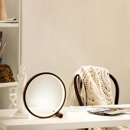 Round lamp on a table with a chair and decorative items in the background
