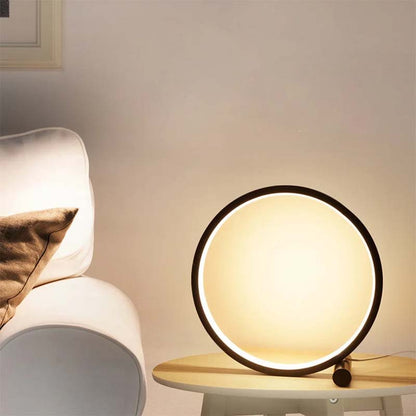 Round table lamp on a side table with a chair and pillow in the background