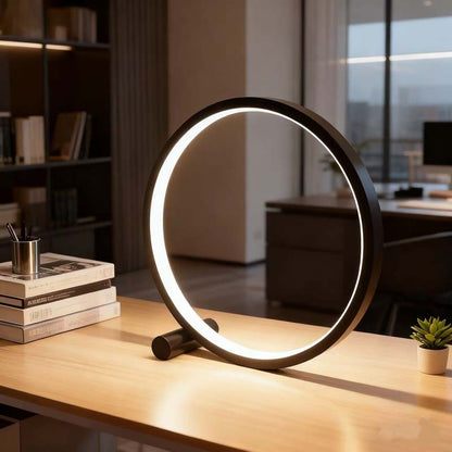 Circular desk lamp on a wooden surface with a blurred office background