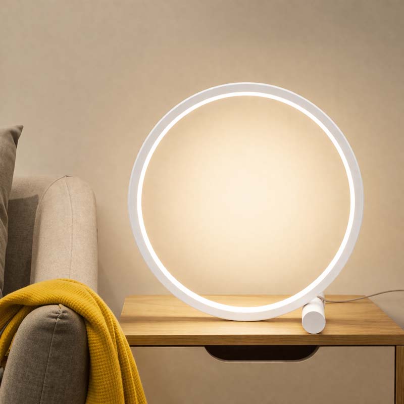 Round table lamp on a wooden side table with a beige sofa and yellow blanket in the background