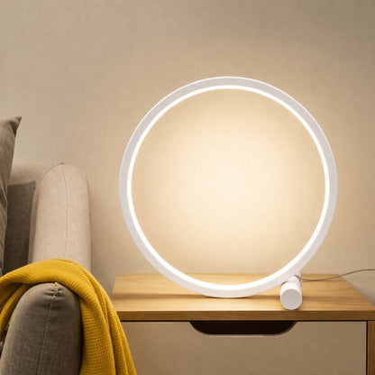 Round table lamp on a wooden side table with a beige sofa and yellow blanket in the background