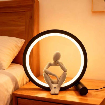 Decorative lamp with a circular light on a wooden nightstand.