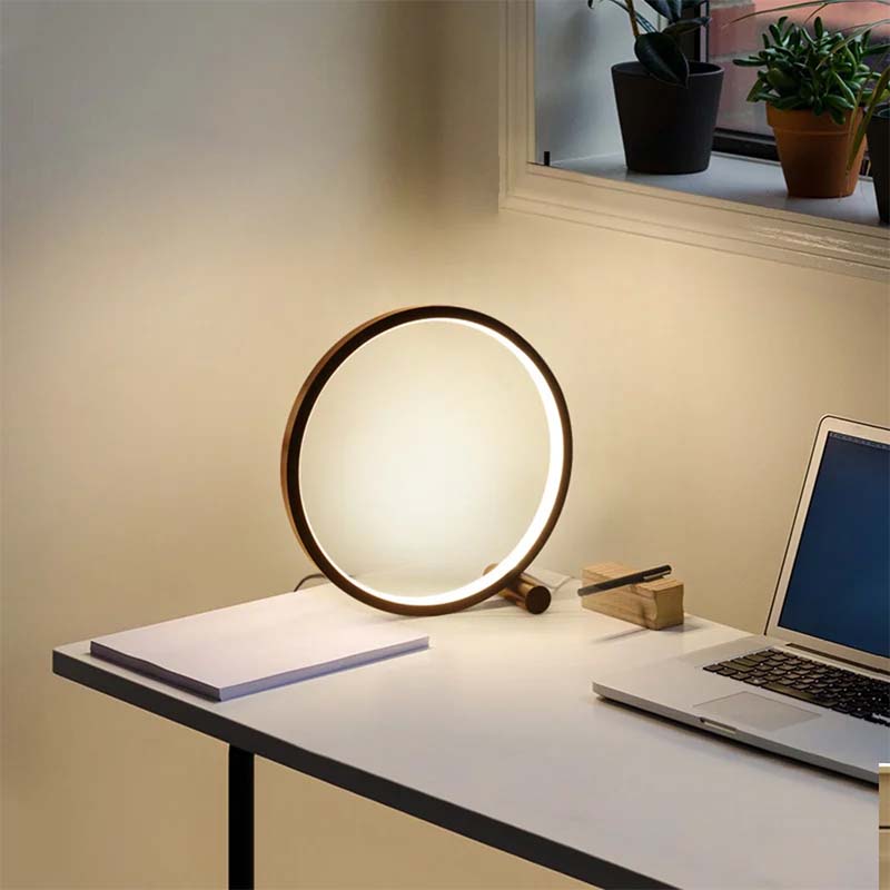 Round table lamp on a desk with a laptop, soft lighting.