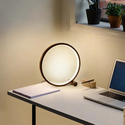 Round table lamp on a desk with a laptop, soft lighting.