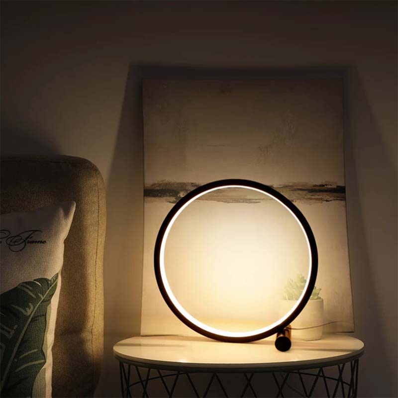 Round table lamp on a marble surface with a soft glow, next to a textured wall and cushion.