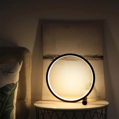 Round table lamp on a marble surface with a soft glow, next to a textured wall and cushion.